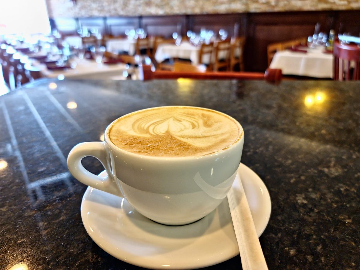 A cappuccino with latte art, the dining room behind